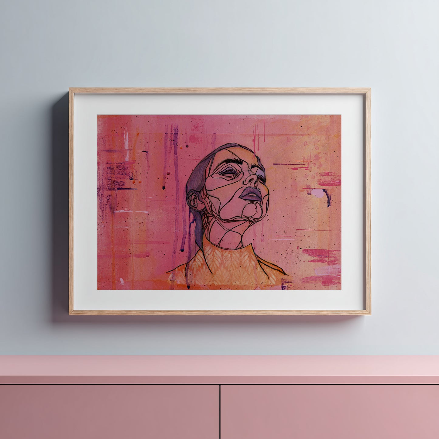 Framed abstract art print of a woman's face on a pink background